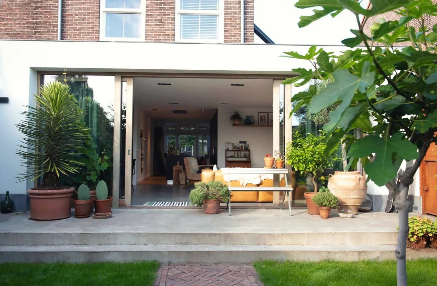 Geopende pui tussen de aanbouw en tuin bij Project Breed