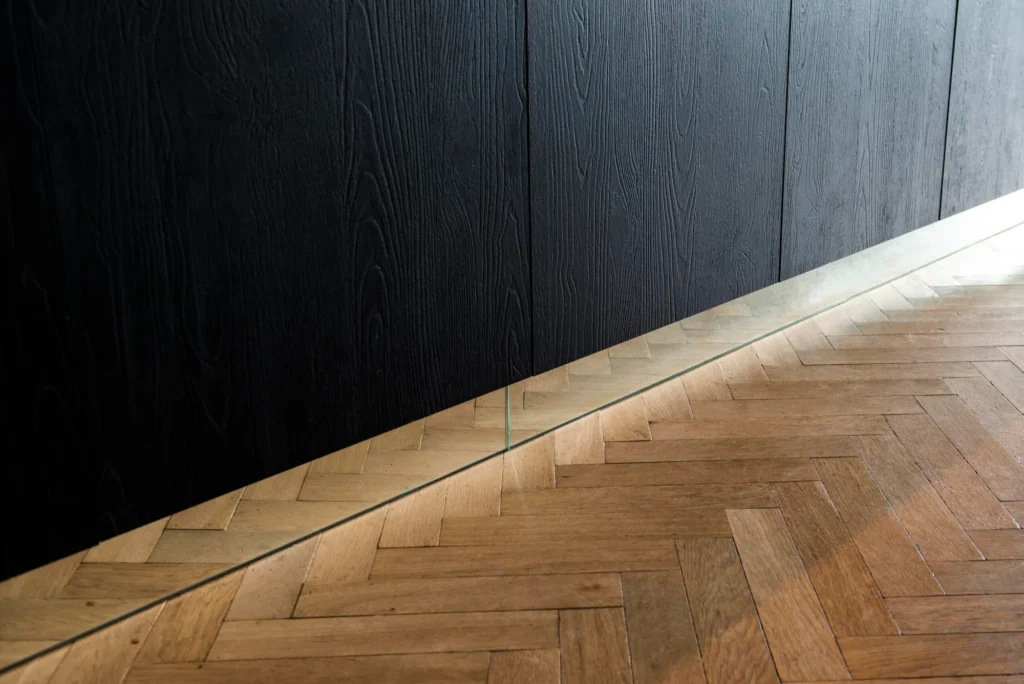 Donkere keukenfronten boven een houten vloer bij Project Breed
