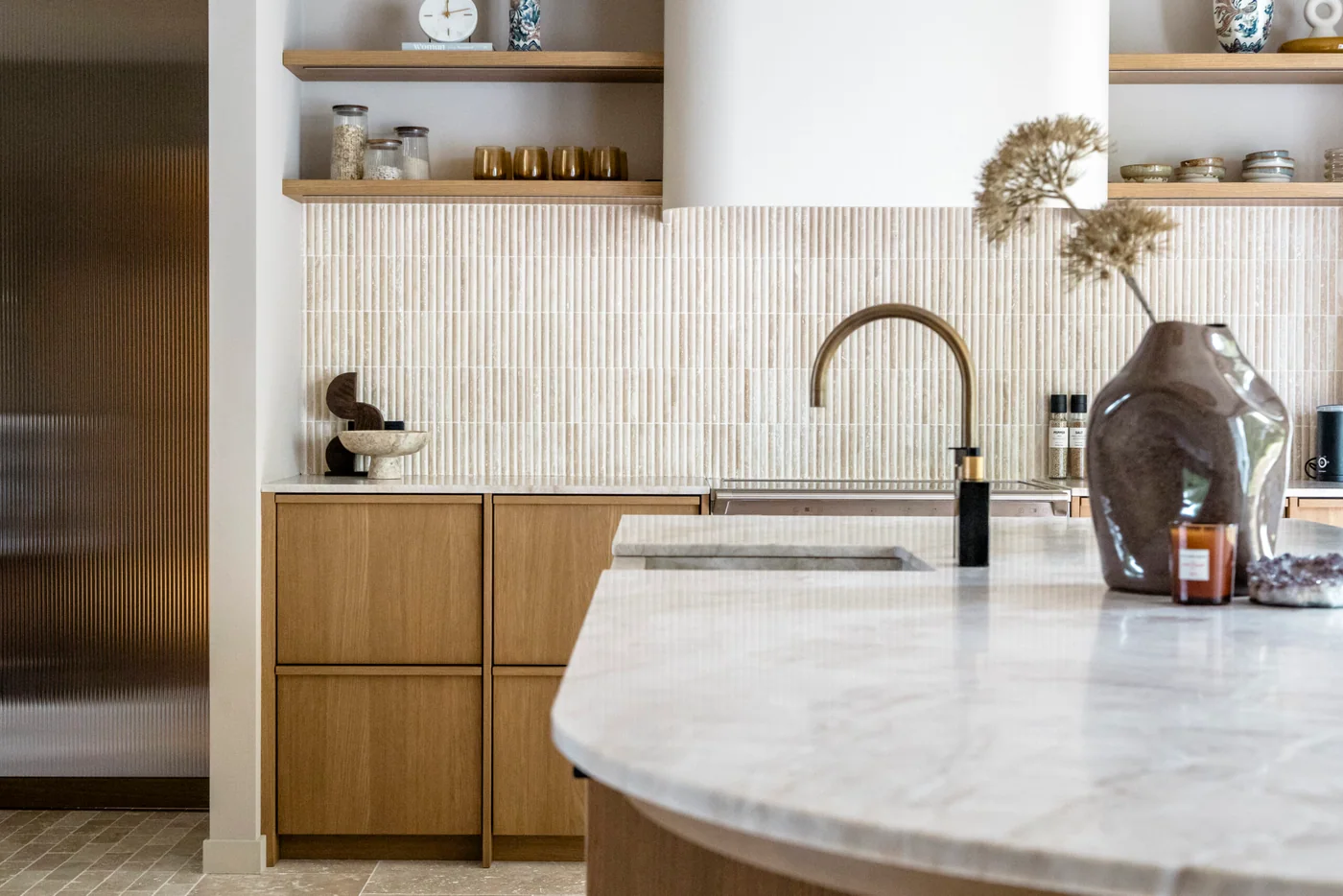 Afgewerkte keuken met houten kasten en een licht natuurstenen werkblad